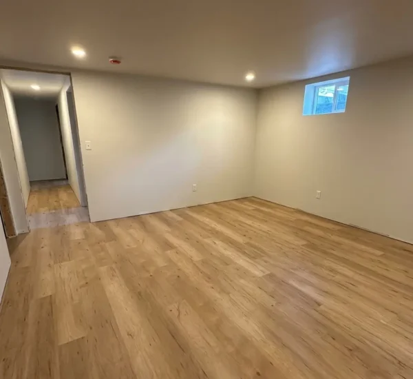 basement-flooring-installation-hallway-n-halleck-portland Newly installed light oak luxury vinyl plank flooring extending across a spacious finished basement room and hallway with recessed ceiling lights on N Halleck St in Portland, installed by Interstate Flooring