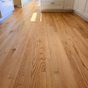 Refinished red oak hardwood floor in a bright kitchen by Interstate Flooring on SW Ridgewood Ave in Portland, Oregon, showing a satin finish, natural wood grain, and modern white cabinetry