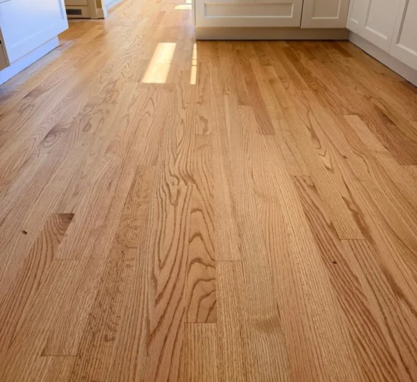 hardwood-floor-refinishing-kitchen-sw-ridgewood-ave-portland Refinished red oak hardwood floor in a bright kitchen by Interstate Flooring on SW Ridgewood Ave in Portland, Oregon, showing a satin finish, natural wood grain, and modern white cabinetry