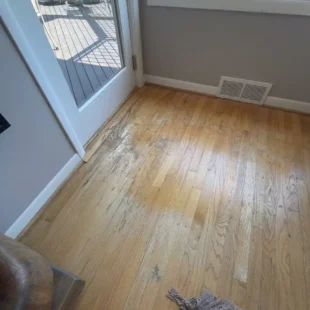 Before photo of a hardwood floor refinishing project on SW Ridgewood Ave in Portland, OR, showing heavy finish wear, discoloration, and scuffs on oak wood flooring next to a glass patio door