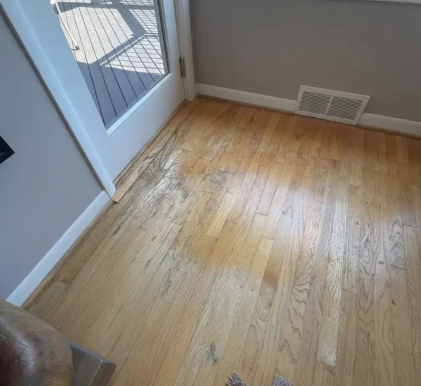 hardwood-floor-refinishing-patio-door-before-sw-ridgewood-ave-portland Before photo of a hardwood floor refinishing project on SW Ridgewood Ave in Portland, OR, showing heavy finish wear, discoloration, and scuffs on oak wood flooring next to a glass patio door