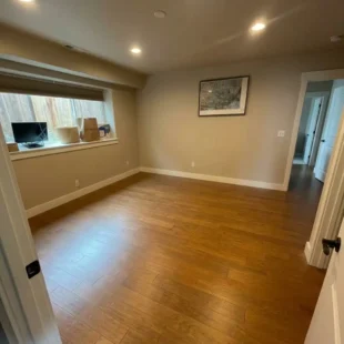hardwood-flooring-installation-bedroom-portland-or Empty bedroom featuring newly installed warm oak hardwood flooring, crisp white baseboards, and recessed lighting in a Portland, Oregon home