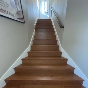 hardwood-stair-installation-portland-or Looking up a completed set of rich brown hardwood stairs with white riser trim and wall handrail in a Portland, Oregon home