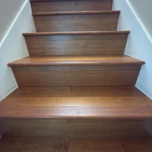 hardwood-stair-treads-installation-portland-or Close-up view looking up a newly completed staircase featuring rich warm hardwood treads and matching wood risers with crisp white side trim in Portland, Oregon