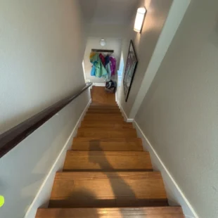 hardwood-stairs-downward-view-portland-or View looking down a completed hardwood staircase with rich brown wooden treads, white wall trim, and dark wood handrail in a Portland, Oregon home