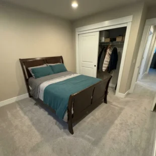 wall-to-wall-carpet-bedroom-portland-or Freshly installed light grey plush carpet in a guest bedroom featuring a dark wood sleigh bed and sliding closet door in Portland, Oregon